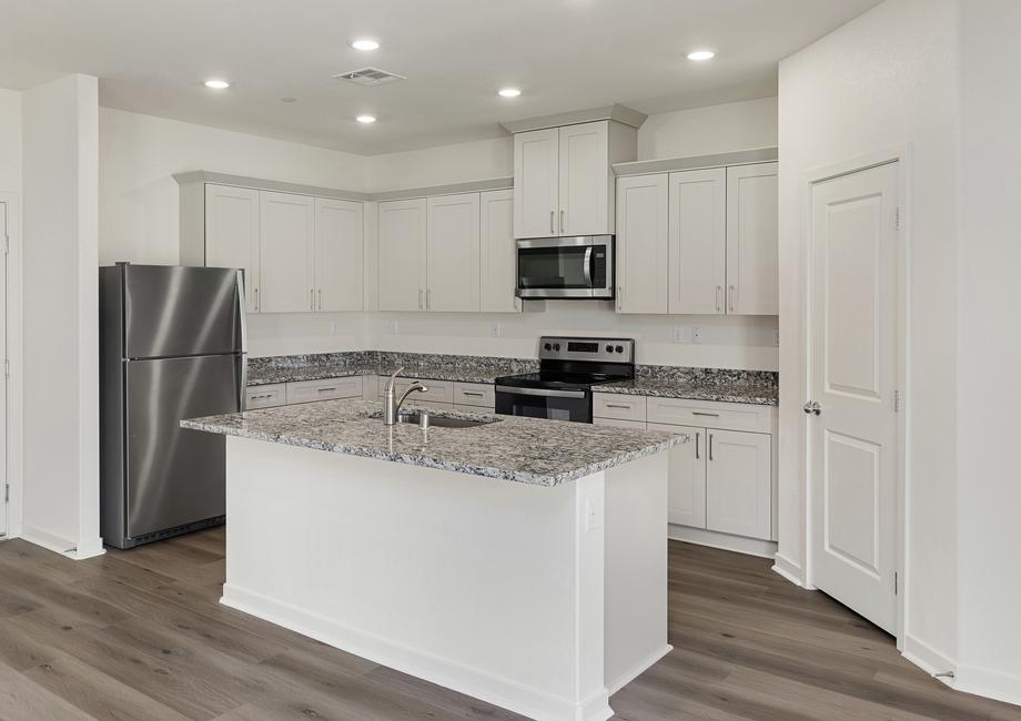 The kitchen has beautiful quartz counters and white cabinets.