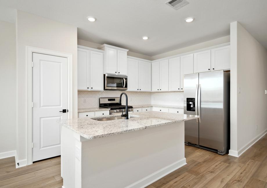 The kitchen has stainless steel appliances and white backsplash.