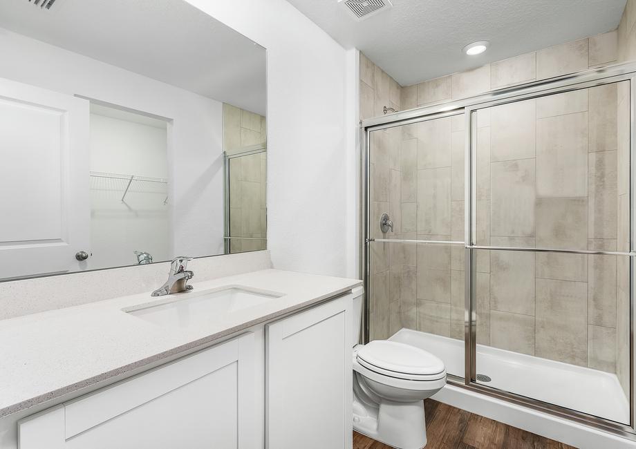 The master bathroom features white cabinets and a walk-in shower.