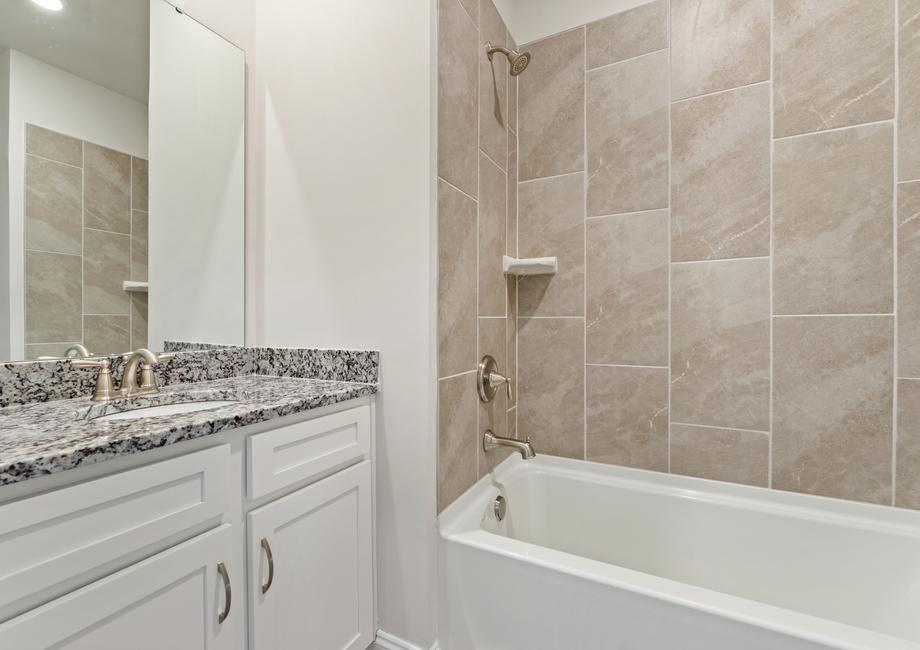 Secondary bathroom with white cabinets.