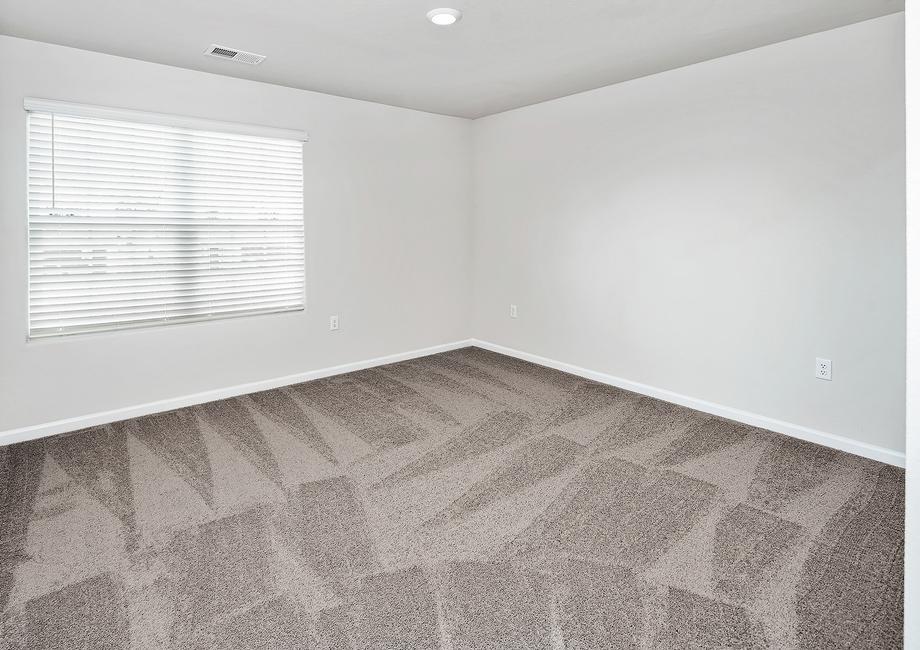 Secondary bedroom with a large window and carpet.