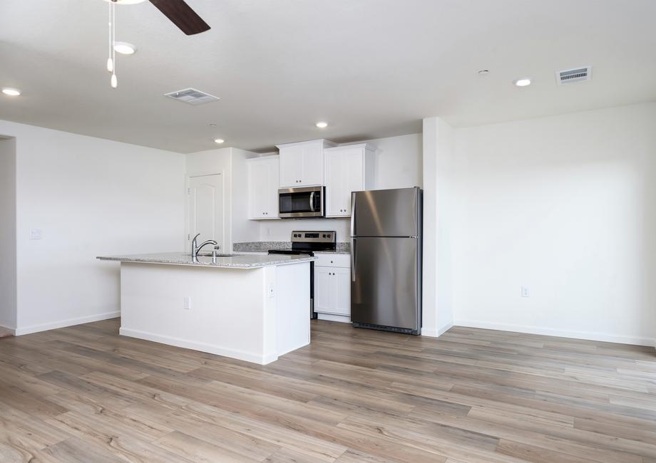 The kitchen has stainless steel appliances and plank flooring and is open to the dining area.