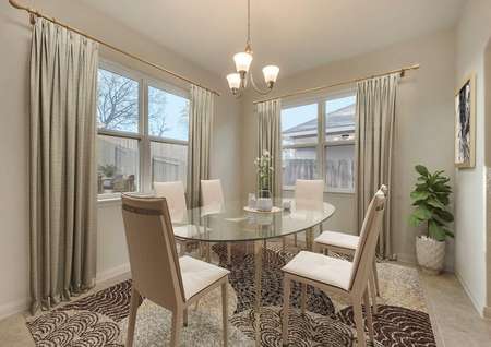 Staged formal dining room with light tile flooring, table, chairs, vase, and floor rug in the Erie floor plan