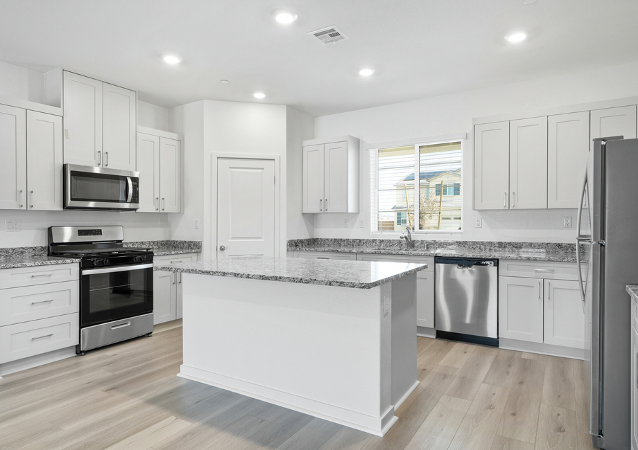 The kitchen has stainless steel appliances and plank flooring.