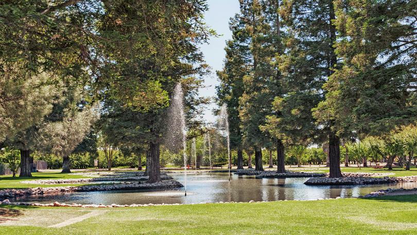 Park in Modesto, California is off of Yosemite Blvd. with picnic area and tables along with lawn, landscaping and beautiful fountains in the small lake.