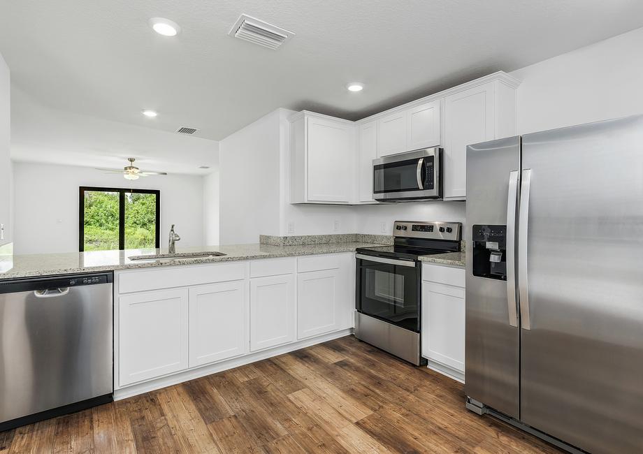 The kitchen includes white cabinets and stainless steel appliances.
