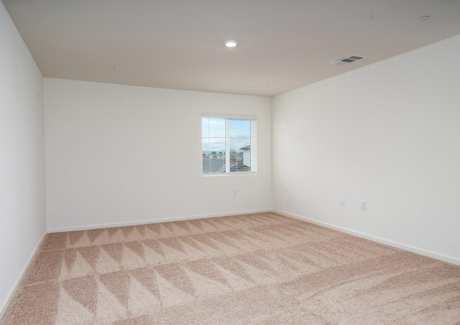 The master bedroom is spacious with carpet.