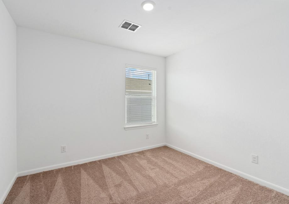 Secondary bedroom with tan carpet, recessed lighting, and a window.