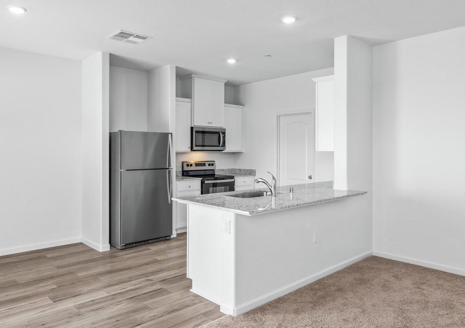 The kitchen has stainless steel appliances and plank flooring.