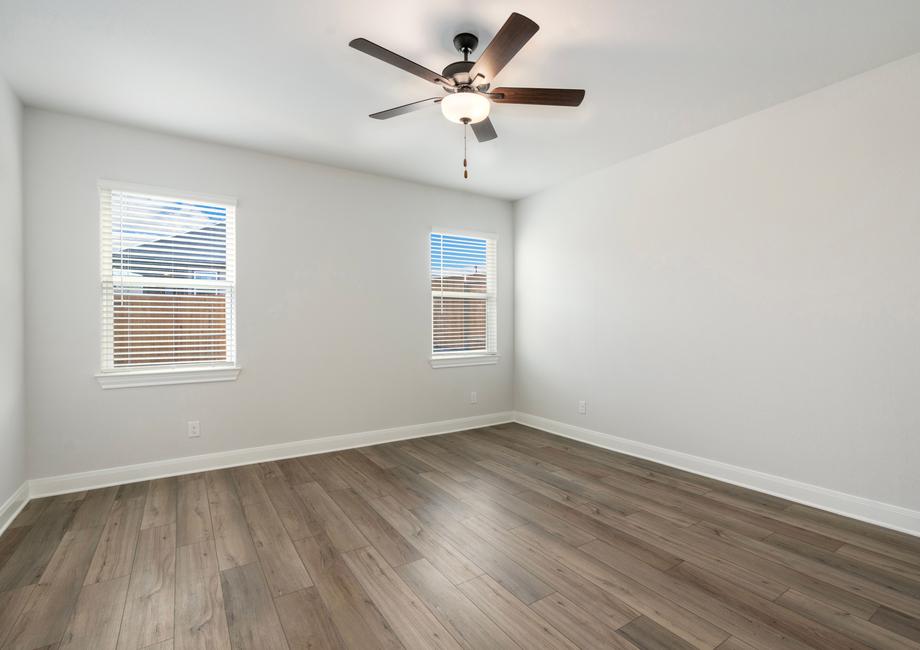 Spacious master bedroom with two windows and a ceiling fan.