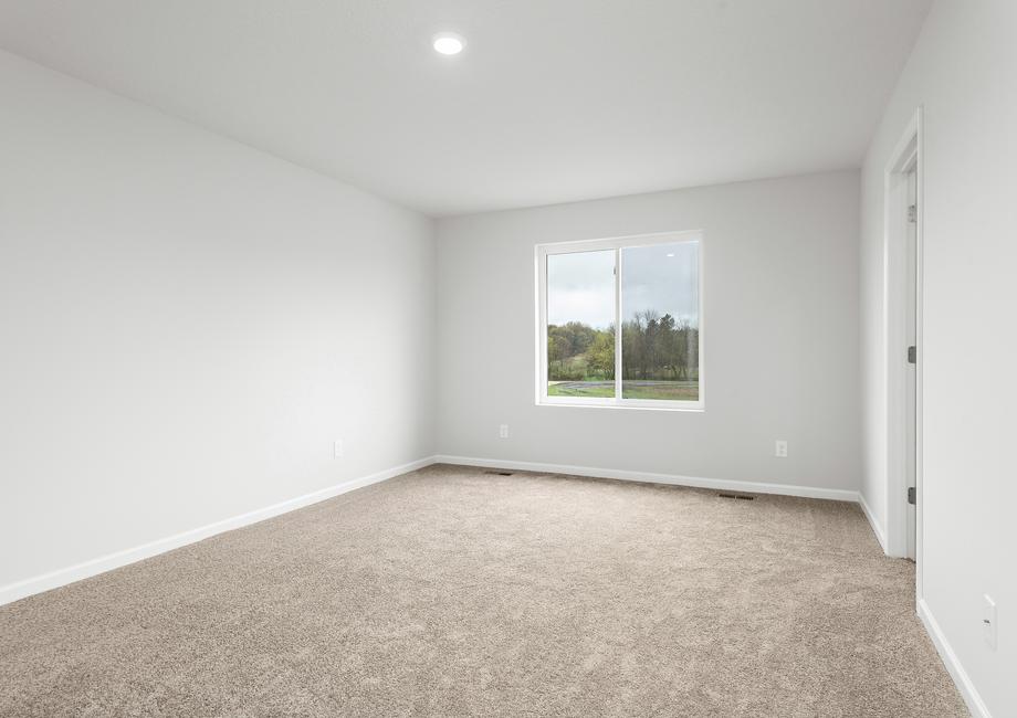 The master bedroom is spacious with a nice window.