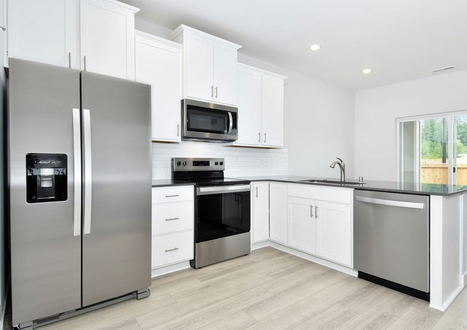 The kitchen has plank flooring and white cabinets.