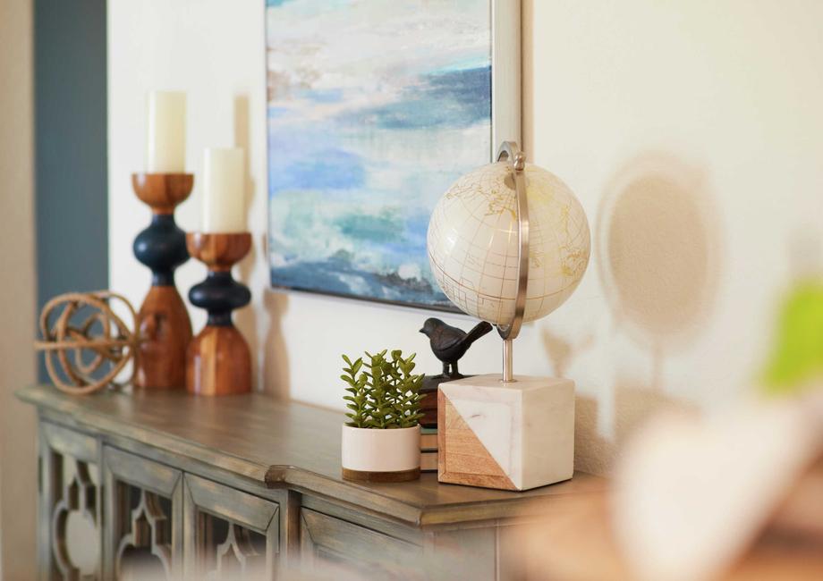 Living room decor with white globe, candles and brown dresser. 