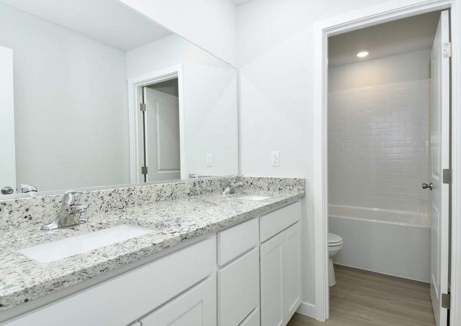 The secondary bathroom has a dual sink vanity and a tub/shower combo.