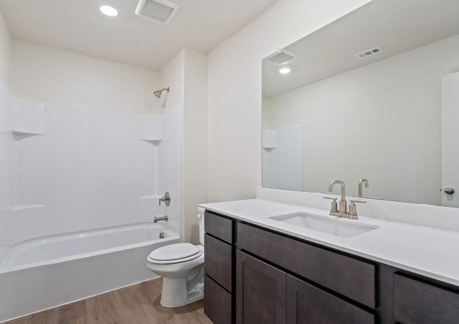 The secondary bathroom has a large vanity space and a shower-tub combo.