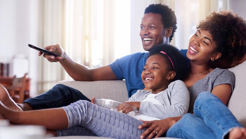 Stock photo of a family watching television together at home.