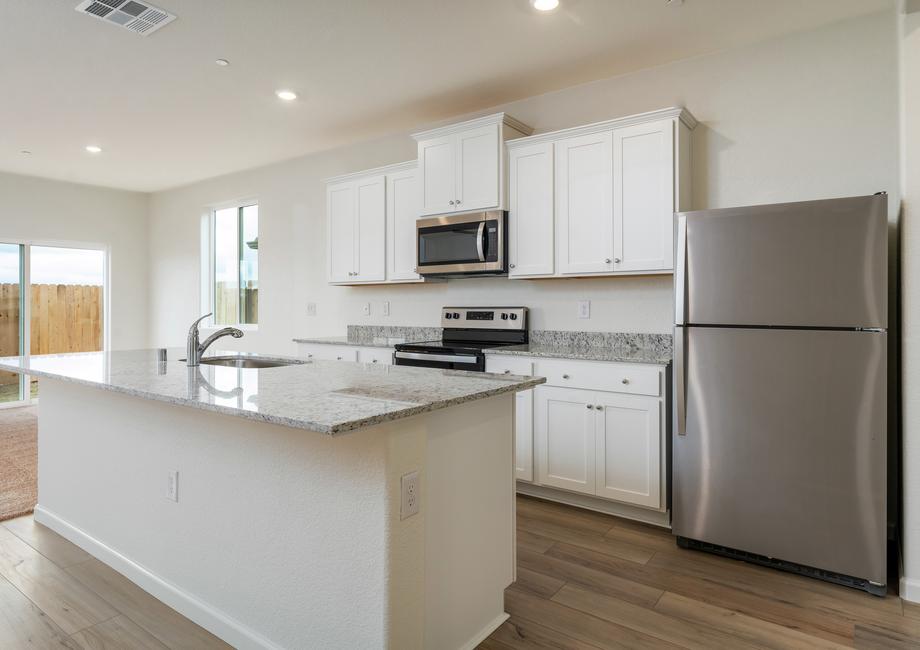 The kitchen has stainless steel appliances and plank flooring and is open to the dining area.
