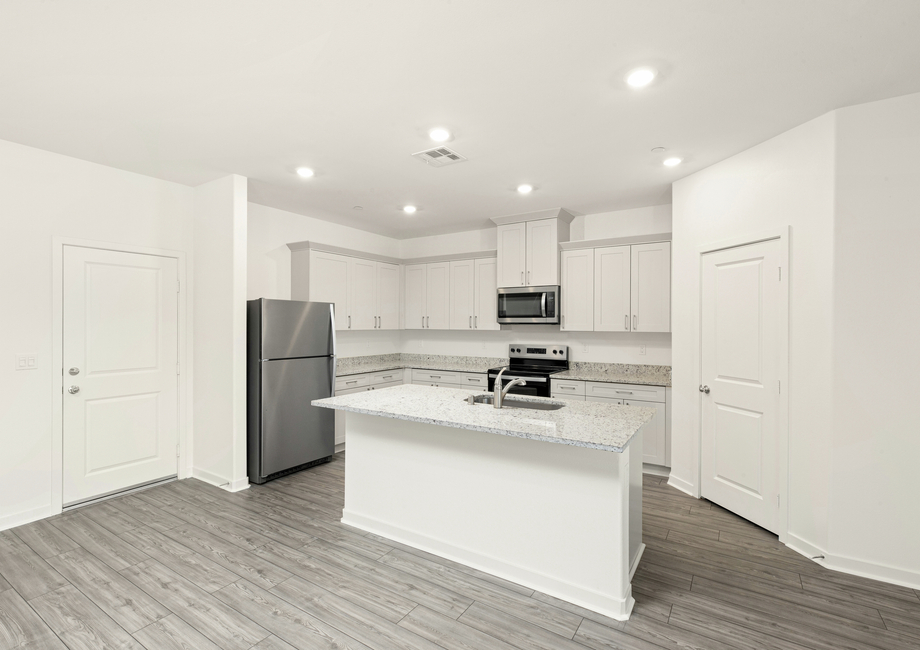 The kitchen has plank flooring and stainless steel appliances.