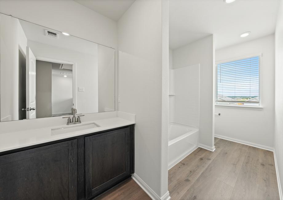 The secondary bathroom has a large vanity space and shower tub combo.