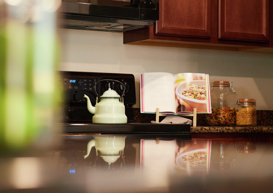 Trace kitchen with white kettle, open cook book and snacks in a jar