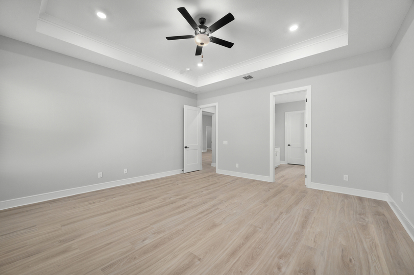 The master bedroom has designer flooring and a ceiling fan.