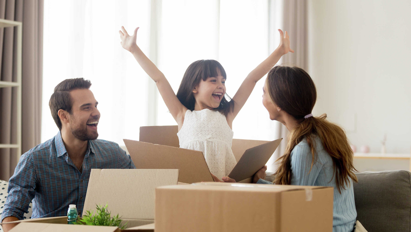 Family unpacking boxes, happy girl with arms in air