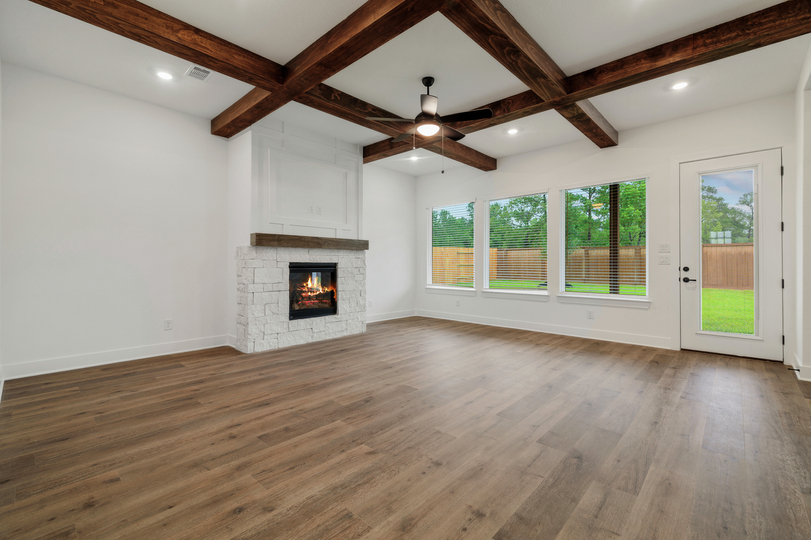 Living room with beam accents and a fireplace. 