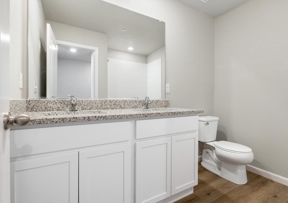 The secondary bathroom has a dual sink vanity and tub/shower combo.