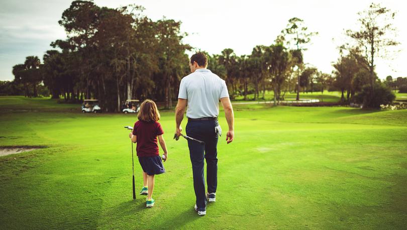 Father and daughter walking on golf course