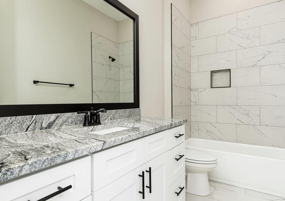 The secondary bathroom features a large framed mirror.