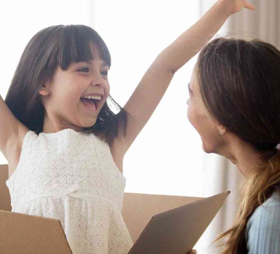 Stock image of family unpacking boxes, little girl excited with hands in the air.