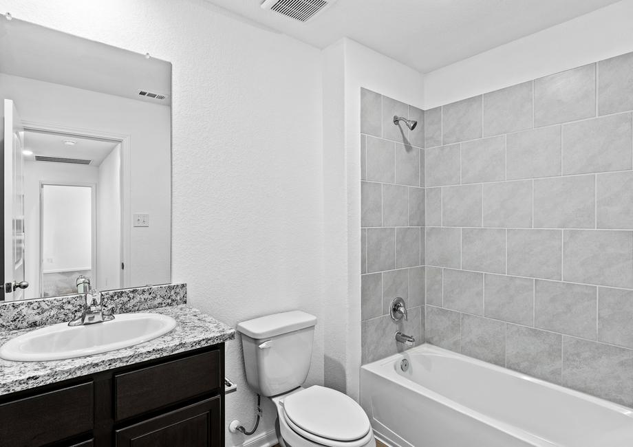 Secondary bathroom with a dual shower and tub, lined with tile.