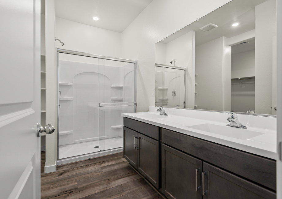 The master bathroom features dual-vanity sinks and a glass-enclosed shower.