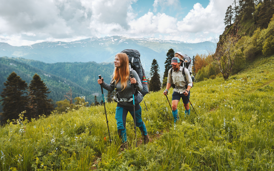 Young couple with their child hiking in the mountains during the summer.