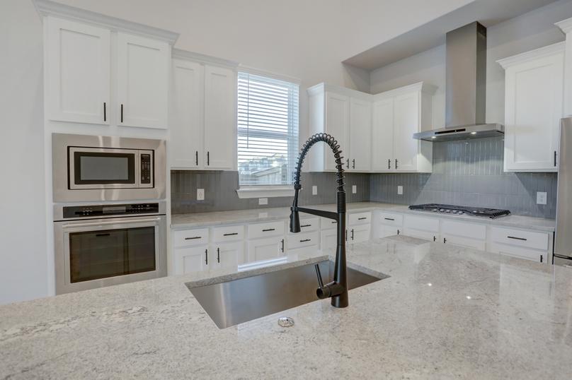 Upgraded kitchen with a tiled backsplash, white cabinetry, and oversized island.