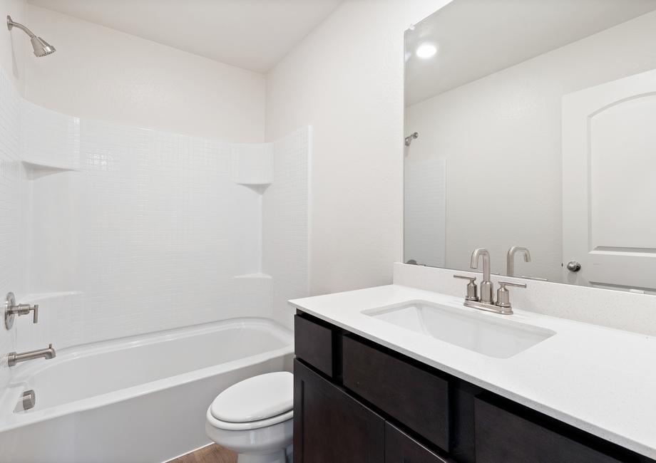 The secondary bathroom has a large vanity space and a shower-tub combo.