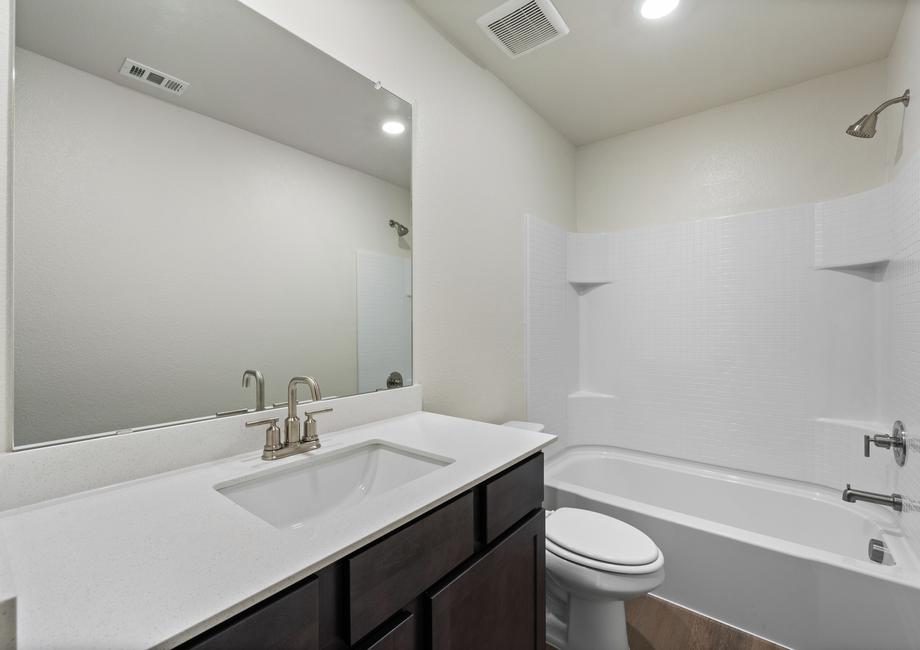 The secondary bathroom has a large vanity space and shower-tub combo.