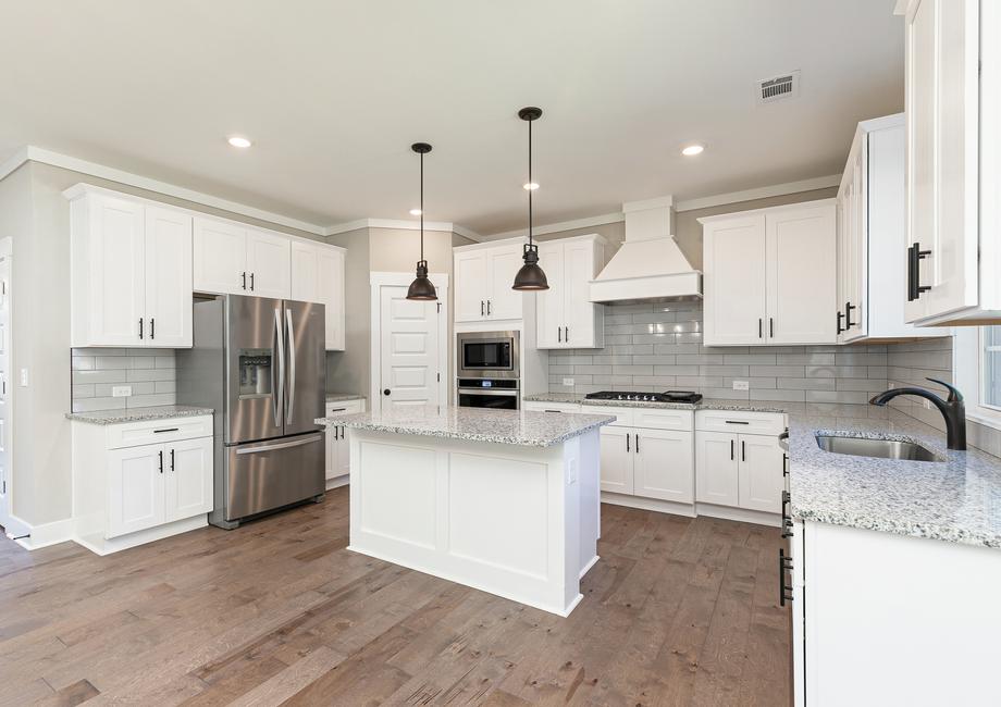 Kitchen with granite countertops, stainless appliances and pendent lights.