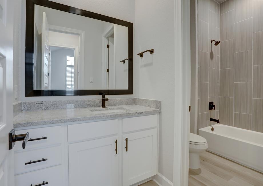 Guest bathroom showcasing a large mirror and white cabinets.