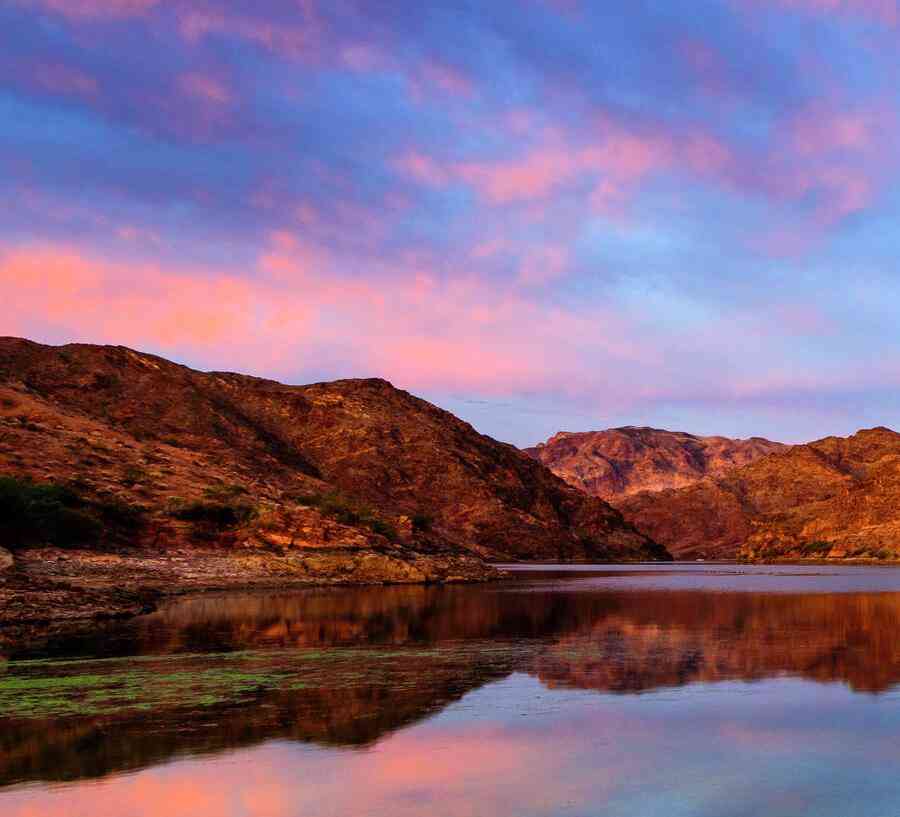 Nevada Colorado River sunrise with the sky reflecting off of the still water and rocky mountains in the background