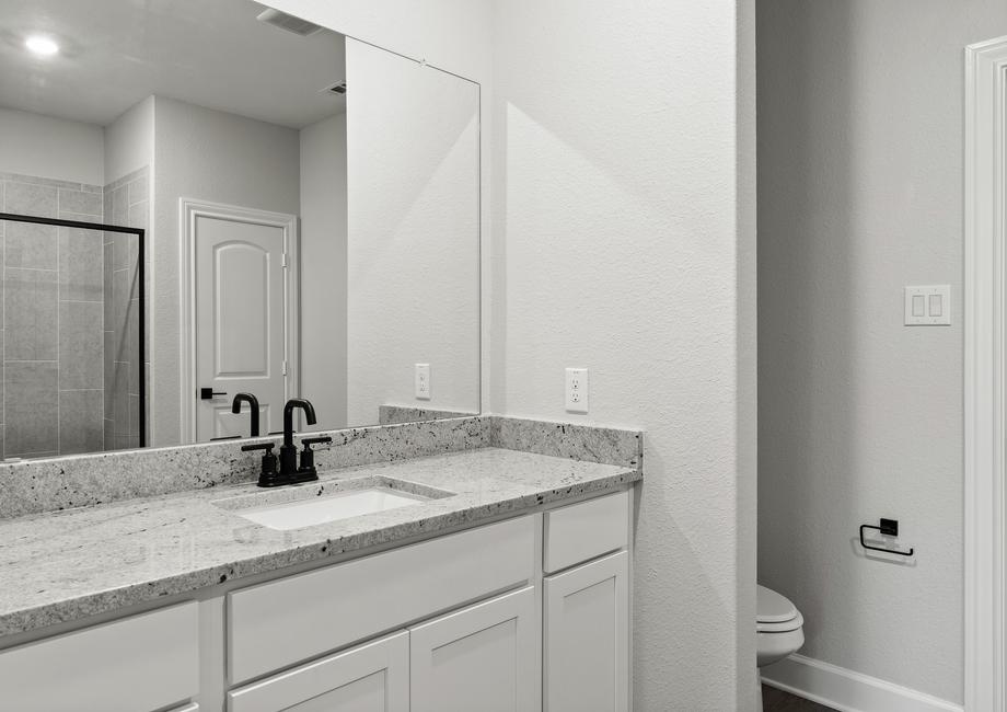 The master bathroom of the Sabine floor plan has a large vanity space with sprawling granite countertops.