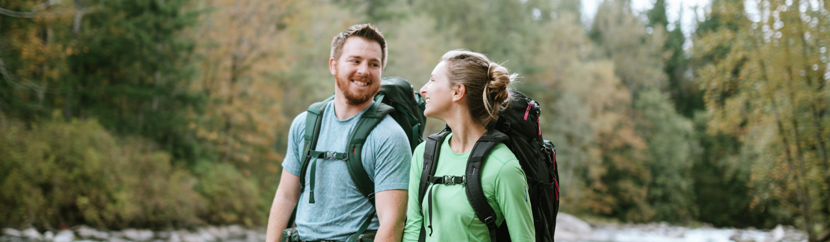 Photo of a young couple backpacking along a river in Washington state in fall.
