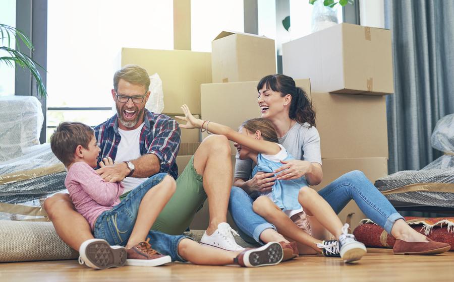 Family sitting on the floor surrounded by moving boxes.