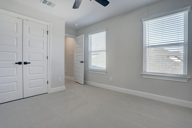 Guest bedroom with a large closet, two windows, and a ceiling fan.