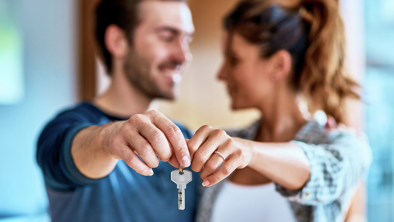 Couple holding up keys to their new home.