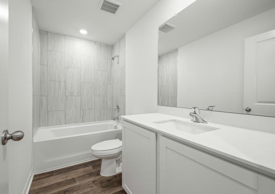 The second bathroom with white cabinets and light gray tile details.