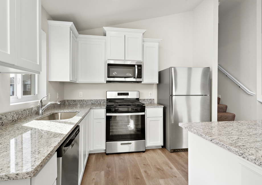 The kitchen has stainless steel appliances and plank flooring.