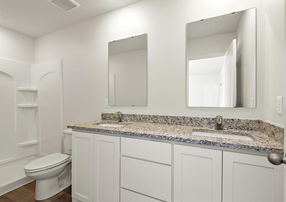 The master bathroom has a dual sink vanity and step in shower. 