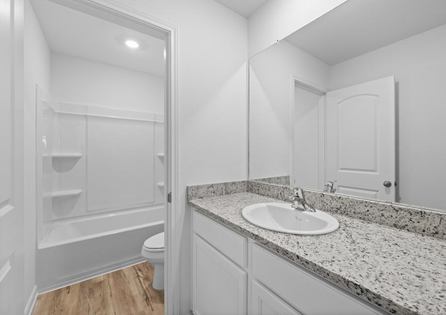 A secondary bathroom with granite countertops