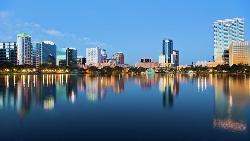 Orlando, Florida skyline at sunrise from Lake Eola showing calm waters and large office buildings reflecting in the water